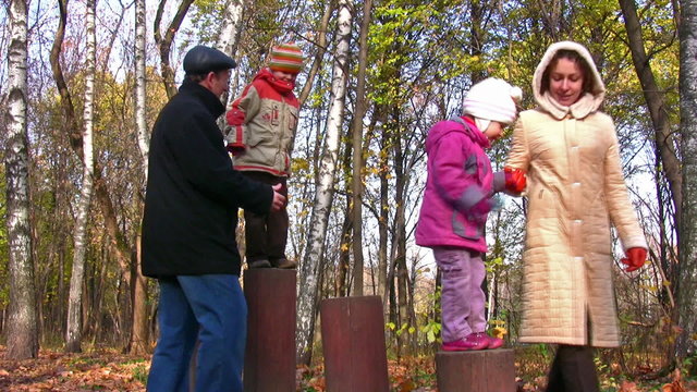 senior with children and mother play in park on stiles