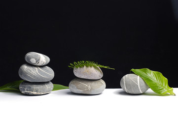 Stack stones on black with green leaf