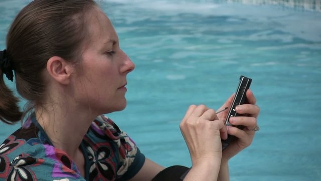 femme tapant un texto au bord de la piscine