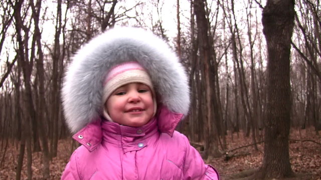 Walking little girl in winter park to camera