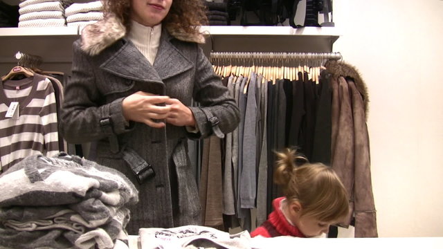 mother with little girl try fit clothes in shop