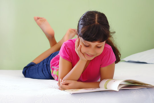 Ni&ntilde;a leyendo libro en la cama