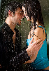 Young amorous happy couple embracing at summer rain