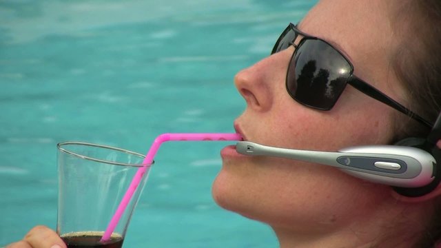 femme buvant et t&eacute;l&eacute;phonant au bord de la piscine