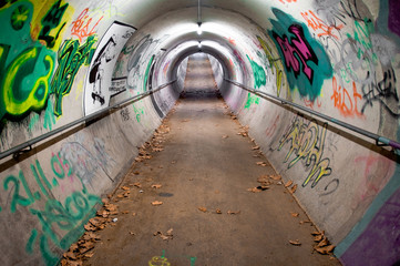 A long pedestrian tunnel covered with graffiti and neon lights