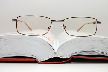 spectacles laying on the open book
