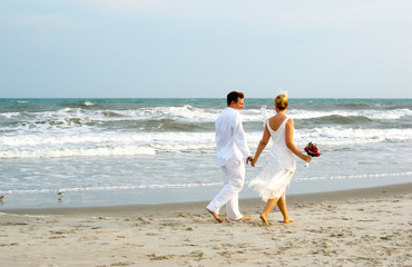 Newly weds walking along the ocean