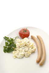 Kartoffelsalat mit zwei Wuerstchen und eine Tomate