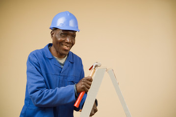Construction worker holding hammer on ladder