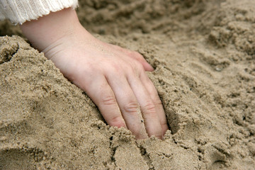 childs hand in sand