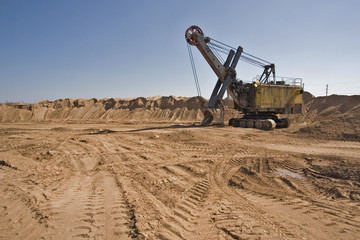 Rusty old yellow excavator on a sand