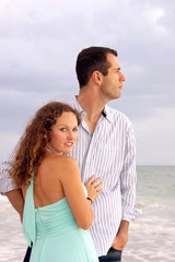 attractive couple at ocean he is looking at sea she is looking a