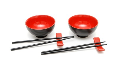 Two sets of chopsticks on stands and the red and black bowls