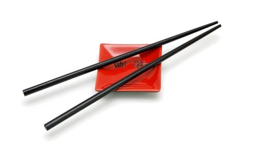 Chopsticks on  small red square saucer with kanji isolated