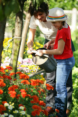 petite fille arrosant des fleurs dans le jardin