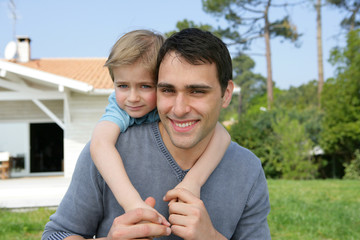 Petit garçon acollé à son père sans un jardin