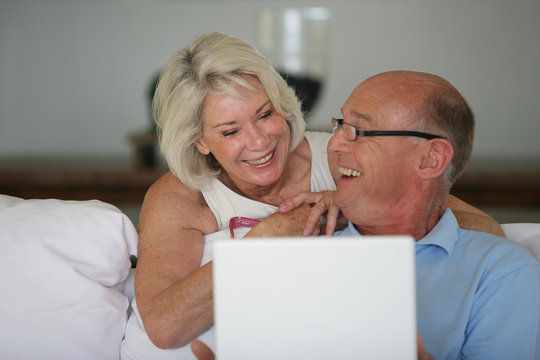 Couple de seniors souriants devant un ordinateur portable