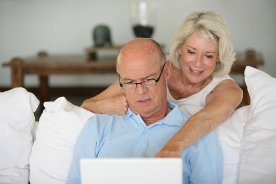 homme et femme senior souriants devant un ordinateur portable