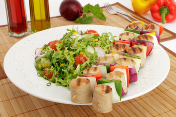 Gegrillter Bratwurstspieß an buntem Salat