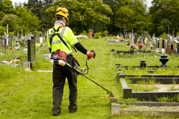 Man cutting grass in graveyard