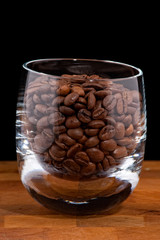 coffea beans in glass on wooden table, black background