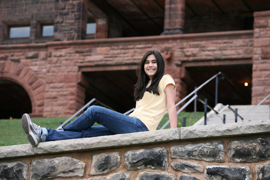 Teen Girl Sitting On Rock Ledge