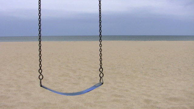 A lone swing at an empty beach on a cloudy gray day