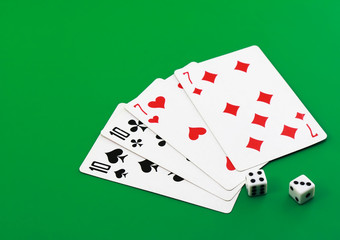 The dice and playing cards on green background