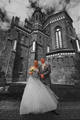 Bride and groom in front of gothic cathedral