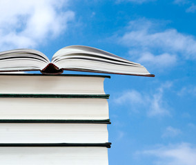 Open book and pile of books isolated on pink background