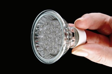 Led bulb in woman's hand on black background
