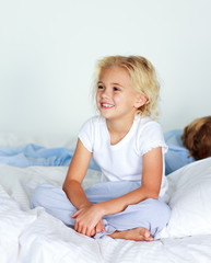 Fototapeta premium Little girl in bed smiling while her brother is sleeping