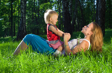 Young mother playing with  daughter on grass