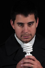 male portrait staring at new light bulb isolated on black