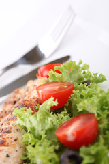 Grilled chicken breasts on a plate with fresh vegetables