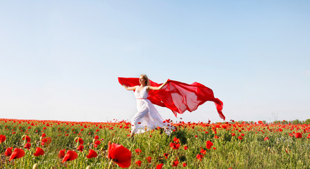 happy woman running with red scarf in poppy field