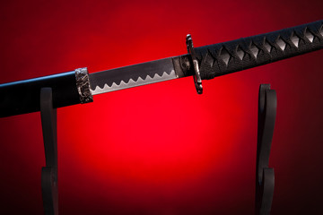 Katana on stand with red lighting, partially drawn blade.