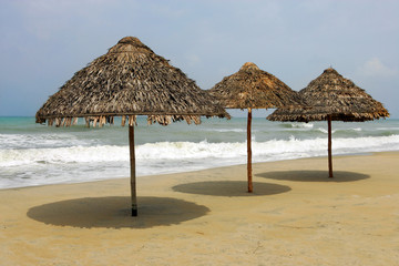Three Thatched umbrellas on deserted beach, Hoi An, Vietnam