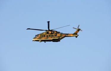 Military helicopter in action on blue sky