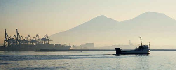 Ferry on a sea with Mount Vesuvius and cranes