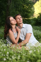 Man and woman sitting on the grass. Looking up