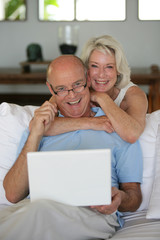 Obraz premium elderly couple smiling with laptop