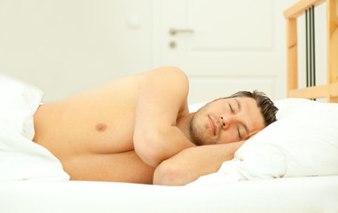 Obraz na płótnie Canvas beautiful man sleeping in a feather bed in sleeping room