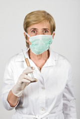 Senior woman doctor with syringe and protective mask