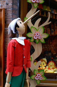 Pinocchio als Holzfigur in Kindergröße vor Spielzeugladen