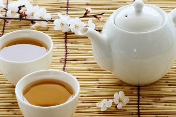 White cup and teapot on bamboo straws