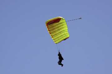 Parachutist in bright blue sky.
