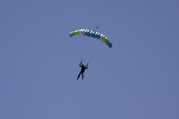 Parachutist in bright blue sky.