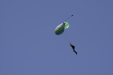 Parachutist in bright blue sky.