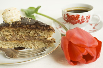 Piece of chocolate cake with red tulip